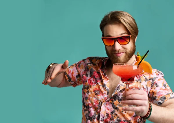 Hombre mantenga rojo margarita cóctel bebida jugo en gafas de sol feliz mirando la mano apuntando a la cámara —  Fotos de Stock