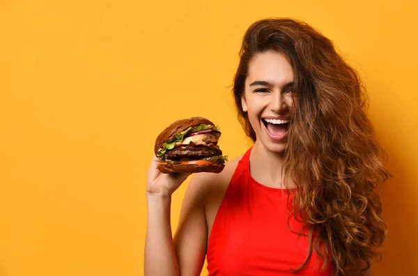 Vrouw houd grote barbecue Hamburger sandwich met hongerige mond gelukkig schreeuwen lachen op gele achtergrond — Stockfoto
