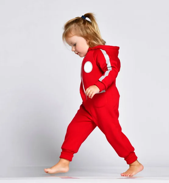 İlk yapım yürüyen küçük bebek kız yürümeye başlayan çocuk kırmızı bez gri adımlar. — Stok fotoğraf