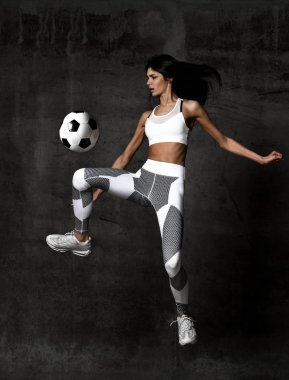 Kadın futbolcu atlar ve Orta Beton çatı duvar topu grev vurmak 