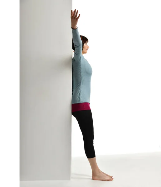 Una donna che si allena dopo il parto. Istruttore di fitness femminile che allunga la colonna vertebrale vicino alla parete in palestra allenarsi esercizi — Foto Stock