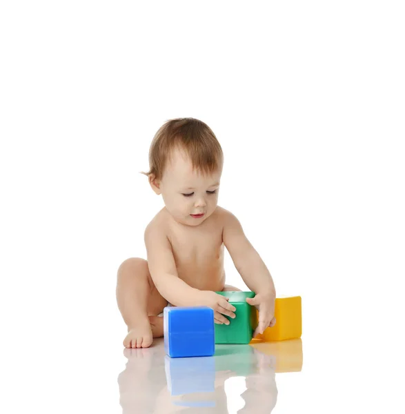 Enfant bébé tout-petit assis en robe avec jouet en brique verte bleue et jaune jouant isolé sur un blanc — Photo