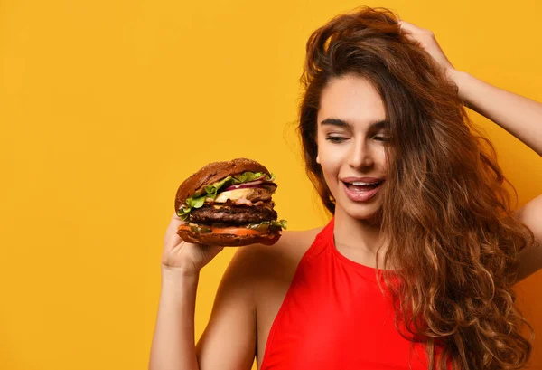 Closeup vrouw kijken naar grote barbecue burger broodje met hongerige mond gelukkig glimlachend op gele achtergrond — Stockfoto