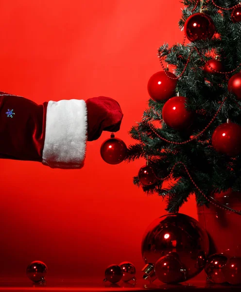 Papai Noel mãos colocar bolas ornamento retalhos vermelhos e artesanato presentes presentes na árvore de Natal ano novo decorado — Fotografia de Stock