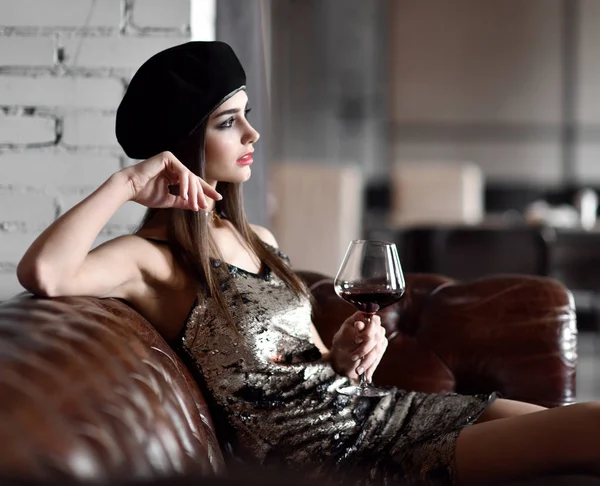 Piękna kobieta nosić czapkę czarny zima picie czerwonego wina w drogiej restauracji — Zdjęcie stockowe