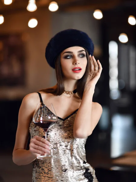 Hermosa mujer usar azul oscuro invierno visón sombrero de piel beber vino tinto en restaurante caro — Foto de Stock