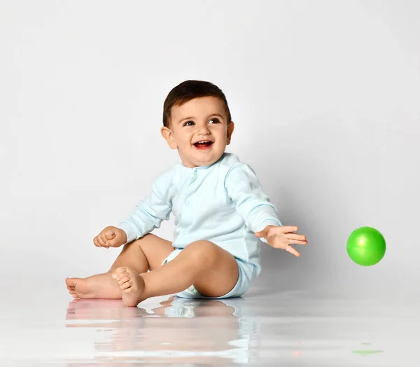 Niño bebé niño niño niño en tela de cuerpo azul claro sentado jugando con bola verde —  Fotos de Stock