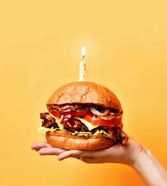 Woman hands hold big tasty burger barbeque sandwich with marble beef and lit candle for birthday party — Stock Photo, Image