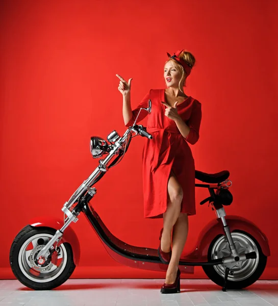 Mulher pinup estilo passeio novo carro elétrico moto scooter de bicicleta presente para o ano novo 2019 apontando dedo na esquina — Fotografia de Stock