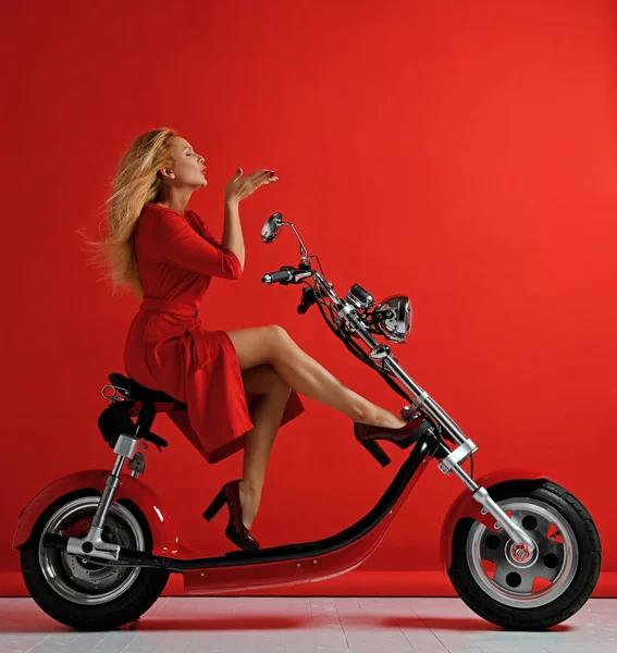 Žena jezdit nové elektrické auto motocykl kolo koloběžka dárek pro nový rok 2019 v červených šatech ránu pusu znamení s rty na červené — Stock fotografie
