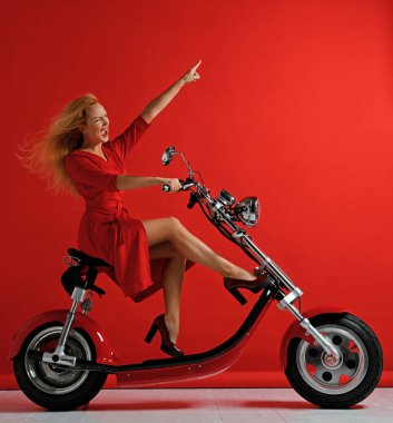 Woman ride new electric car motorcycle bicycle scooter with hands pointing finger up freedom sign laughing smiling clipart