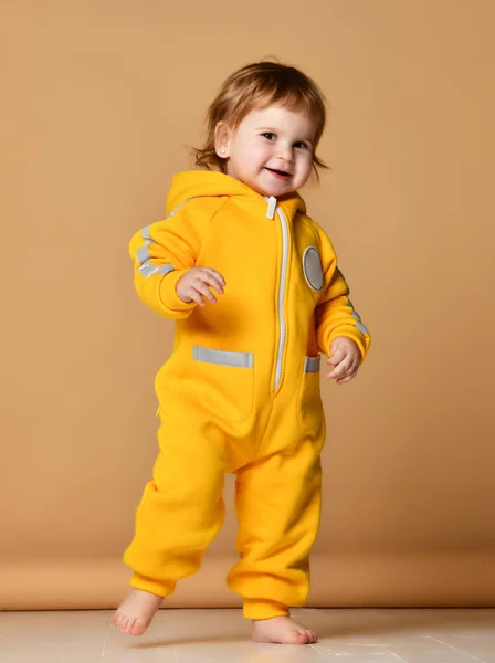 Niño bebé bebé niña niño en invierno mono amarillo hacer primeros pasos feliz sonrisa —  Fotos de Stock