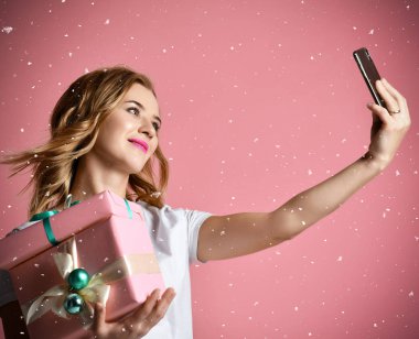 Genç güzel kadın Noel hediye hediyeler gülümseyen tutun ve selfie fotoğraf ile cep telefonunu Mobil olun
