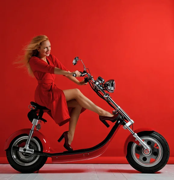 Donna cavalcare nuova bici elettrica moto scooter bici vestito rosso sorpreso — Foto Stock
