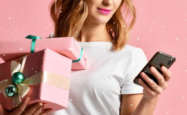 Mobil cep telefonu ile Noel için alışveriş online kadın pembe üzerinde gülümseyen hediyeler sunar