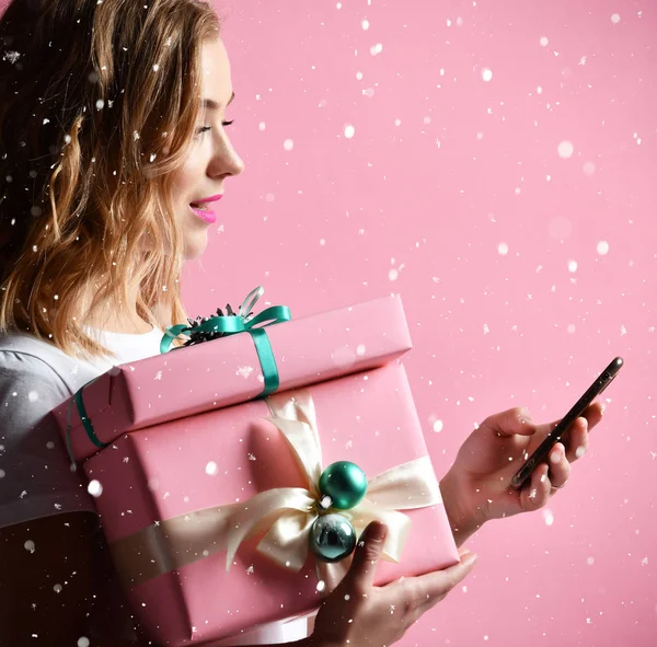 Woman shopping online with mobile cellphone for christmas presents gifts smiling on light pink — Stock Photo, Image