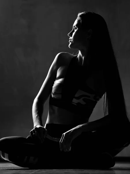 Jovem mulher do esporte em treino pano de exercício posando alongamento no ginásio no fundo cinza escuro — Fotografia de Stock