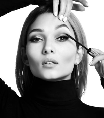 Kadın kirpik makyaj fırça beyaz arka planda siyah rimel uygulayarak