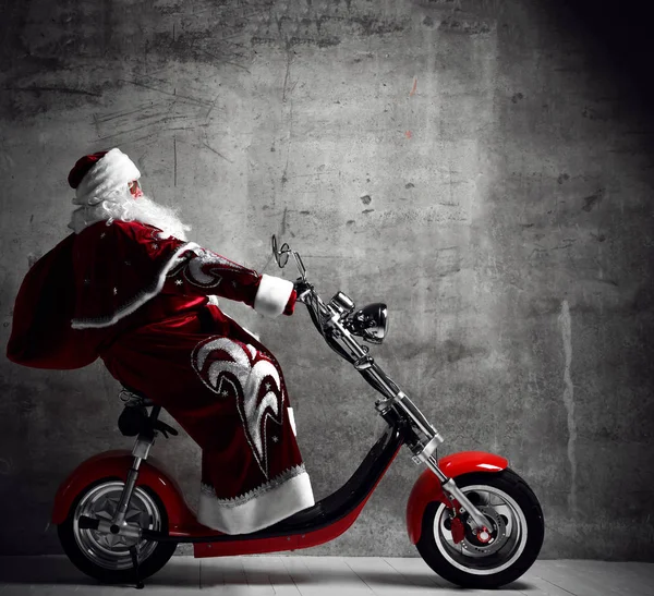 Papai Noel andar de moto scooter de bicicleta com saco cheio de presentes presentes com espaço de cópia de texto. Ano Novo e Feliz Natal — Fotografia de Stock