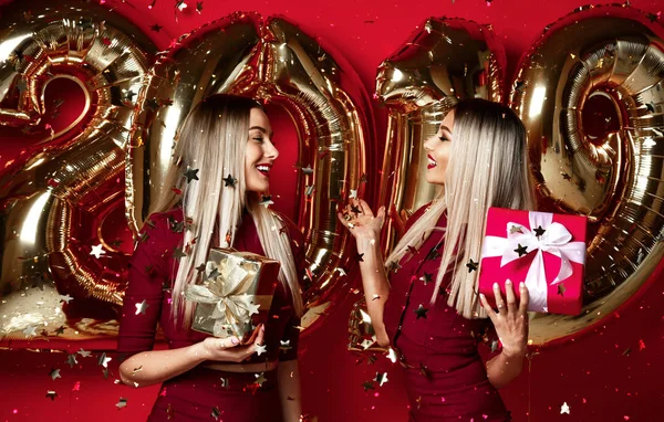 새 해 파티 행복 한 웃는 여자 캐주얼 드레스에 축 하 하는 두 여자 던져 2019 풍선 금 스타 색종이 — 스톡 사진