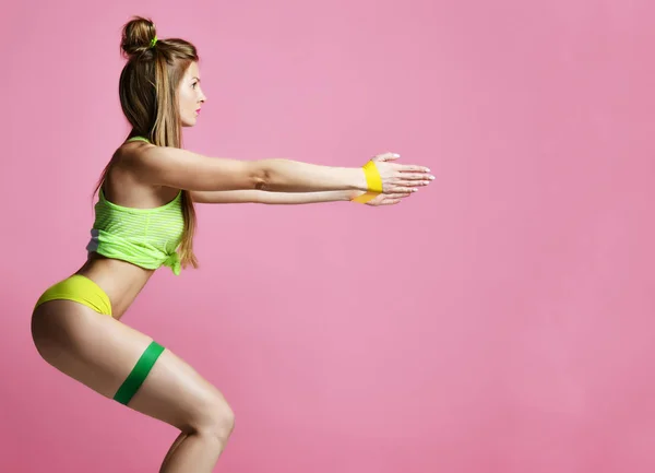 Женщина занимается послеродовой тренировкой. Инструктор по фитнесу, работающая с резиновой лентой на современном розовом — стоковое фото