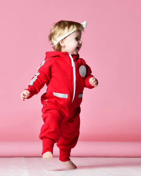 Niño bebé niño niño niño en tela de cuerpo rojo hacer primeros pasos feliz riendo en rosa claro —  Fotos de Stock