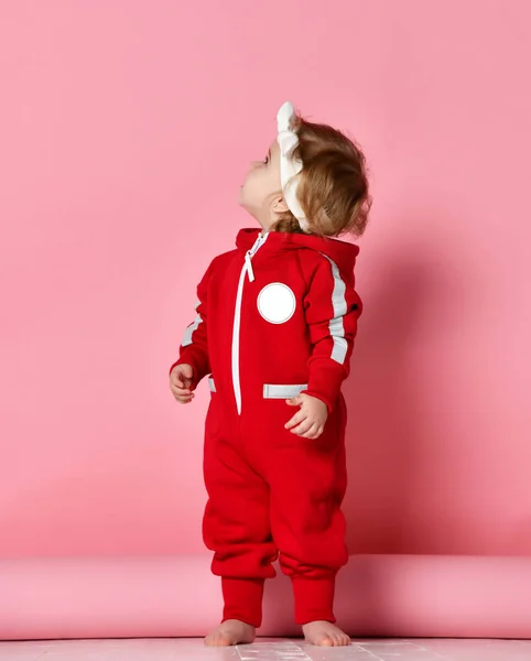 Niño bebé niño niño niño en paño rojizo hacer los primeros pasos de pie feliz mirando hacia arriba en rosa claro —  Fotos de Stock