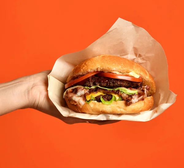 Woman hands hold big burger barbeque sandwich with marble beef on orange