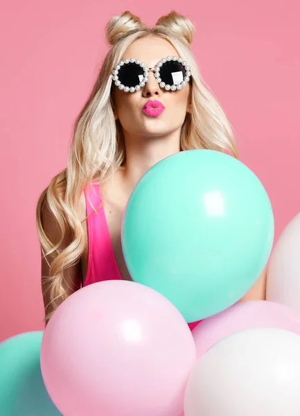 Mujer rubia alegre de moda en fiesta de cumpleaños divirtiéndose con globos de aire de color pastel golpe beso — Foto de Stock