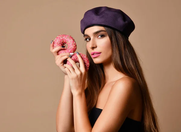 Mujer mantenga dulce rosado azúcar rosquillas boca hambrienta sobre fondo marrón claro — Foto de Stock