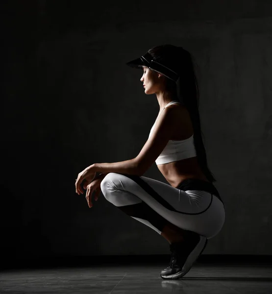 Joven mujer deportiva en ejercicio ejercicio de tela posando estiramiento en el gimnasio sobre fondo gris oscuro — Foto de Stock