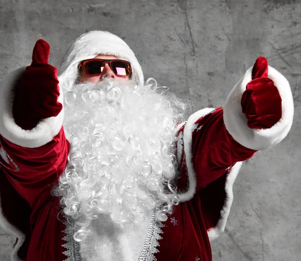 Santa Claus muestra los pulgares bajo el confeti de nieve. Año nuevo y Feliz Navidad — Foto de Stock