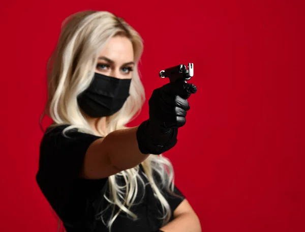 Жінка косметолог косметолог тримати вухо пірсинг пістолета в чорний медичні рукавички і маски на червоне — стокове фото