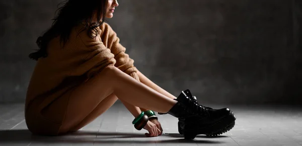 Jovem mulher de moda loira sexy sentada no chão em blusa de malha sexy no escuro — Fotografia de Stock