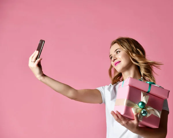 Joven hermosa mujer celebrar regalos de Navidad sonriendo y hacer foto selfie con su teléfono móvil —  Fotos de Stock