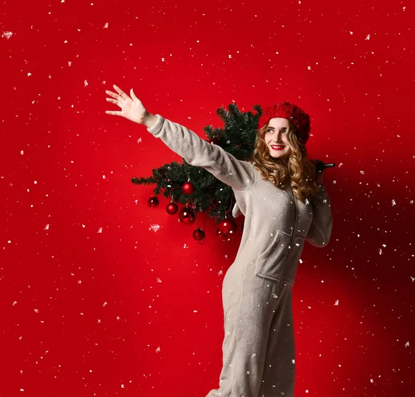 Mujer joven celebrar invierno decoración de abeto de Navidad en el sombrero de punto bajo la nieve. Concepto de año nuevo — Foto de Stock