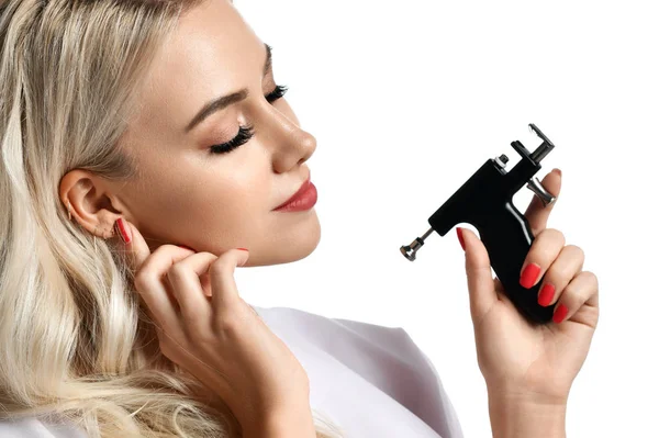 Mujer esteticista cosmetólogo mantenga Piercing de oído pistola mirando a la esquina aislado en blanco —  Fotos de Stock