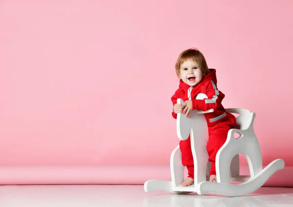 Sallanan sandalye oyuncak at üstünde pembe ışık üzerinde sallanan Toddler bebek kız sürme — Stok fotoğraf