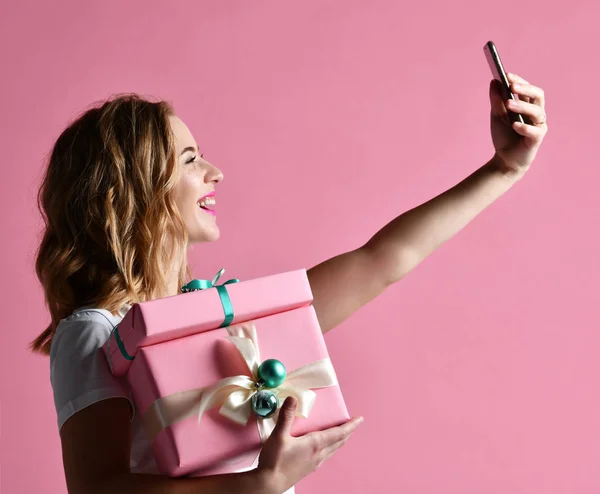 Joven hermosa mujer celebrar regalos de Navidad sonriendo y hacer foto selfie con su teléfono móvil —  Fotos de Stock