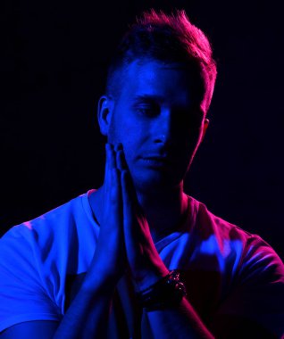 Seksi adam kas vücut ve beyaz tişört Neon ışık portre göstermek dua el işaretiyle karanlık 