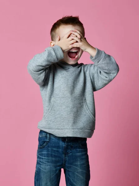 Bebé niño cubriendo cerrar los ojos con las manos y las palmas gritando riendo sobre rosa —  Fotos de Stock