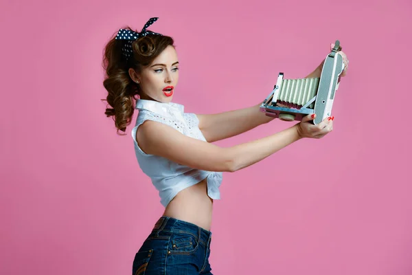 Joven pinup estilo mujer tomar foto uso antiguo portátil foto cámara medio marco en rosa claro — Foto de Stock