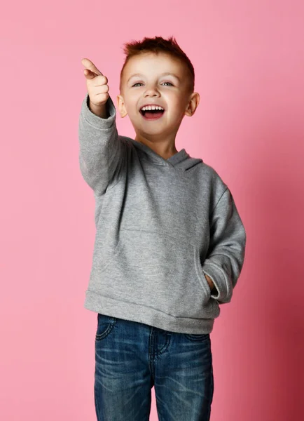 Jovem garoto de capuz cinza apontando um dedo na esquina sorrindo isolado no rosa — Fotografia de Stock