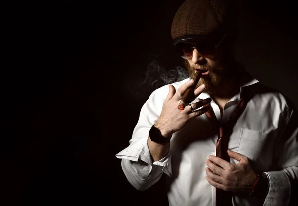 Brutal homem de negócios chefe fumar charuto em óculos escuros marrons, camisa branca e chapéu — Fotografia de Stock