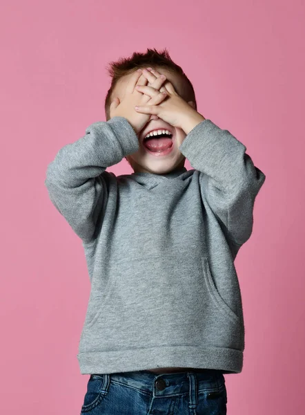 Bebé niño cubriendo cerrar los ojos con las manos y las palmas gritando riendo sobre rosa —  Fotos de Stock