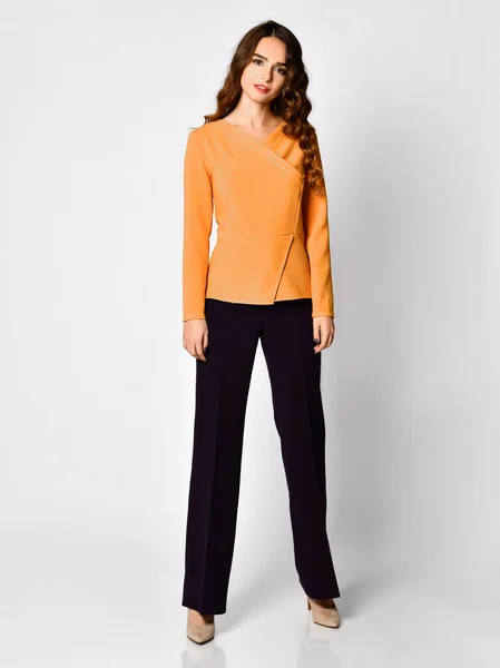 Jeune belle femme brune posant dans un nouveau pull chemisier jaune orange décontracté et pantalon noir corps entier — Photo