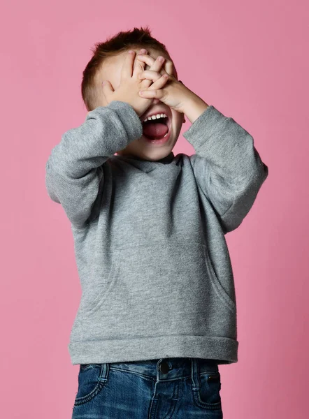 Bebé niño cubriendo cerrar los ojos con las manos y las palmas gritando riendo sobre rosa —  Fotos de Stock