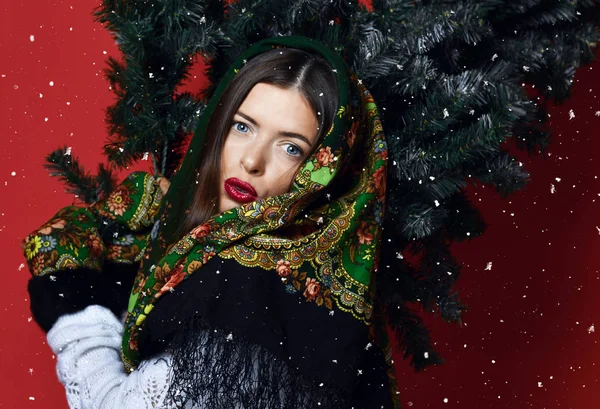 Glückliche russische Frau mit Schal hält Weihnachtsbaum auf ihren Schultern glücklich lachend — Stockfoto