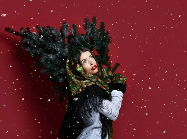 Gelukkig Russische stijl vrouw met sjaal greep kerstboom op haar schouders gelukkig lachen — Stockfoto