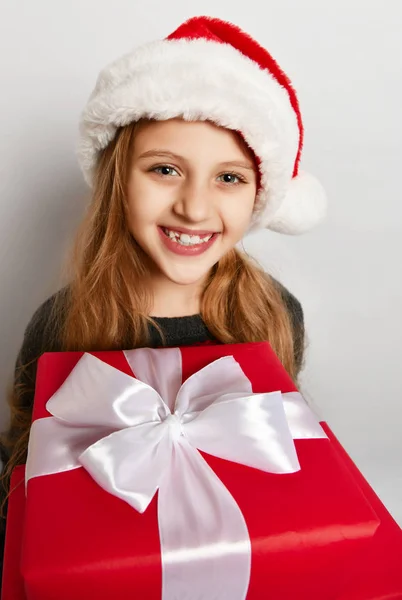 Sorridente bambino bambina di Natale in x-mas cappello di Babbo Natale con scatola regalo rossa felice sorridente — Foto Stock